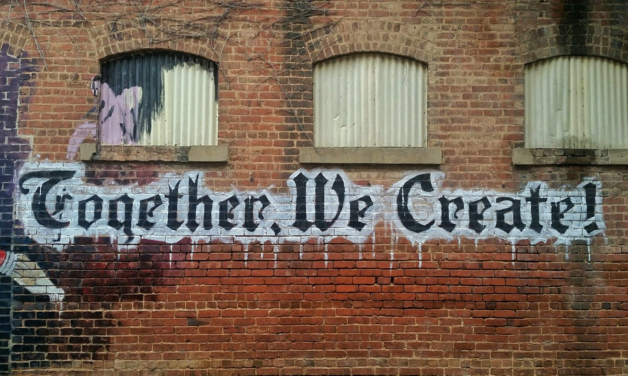 Graffiti: Together, We Create! on a brick wall