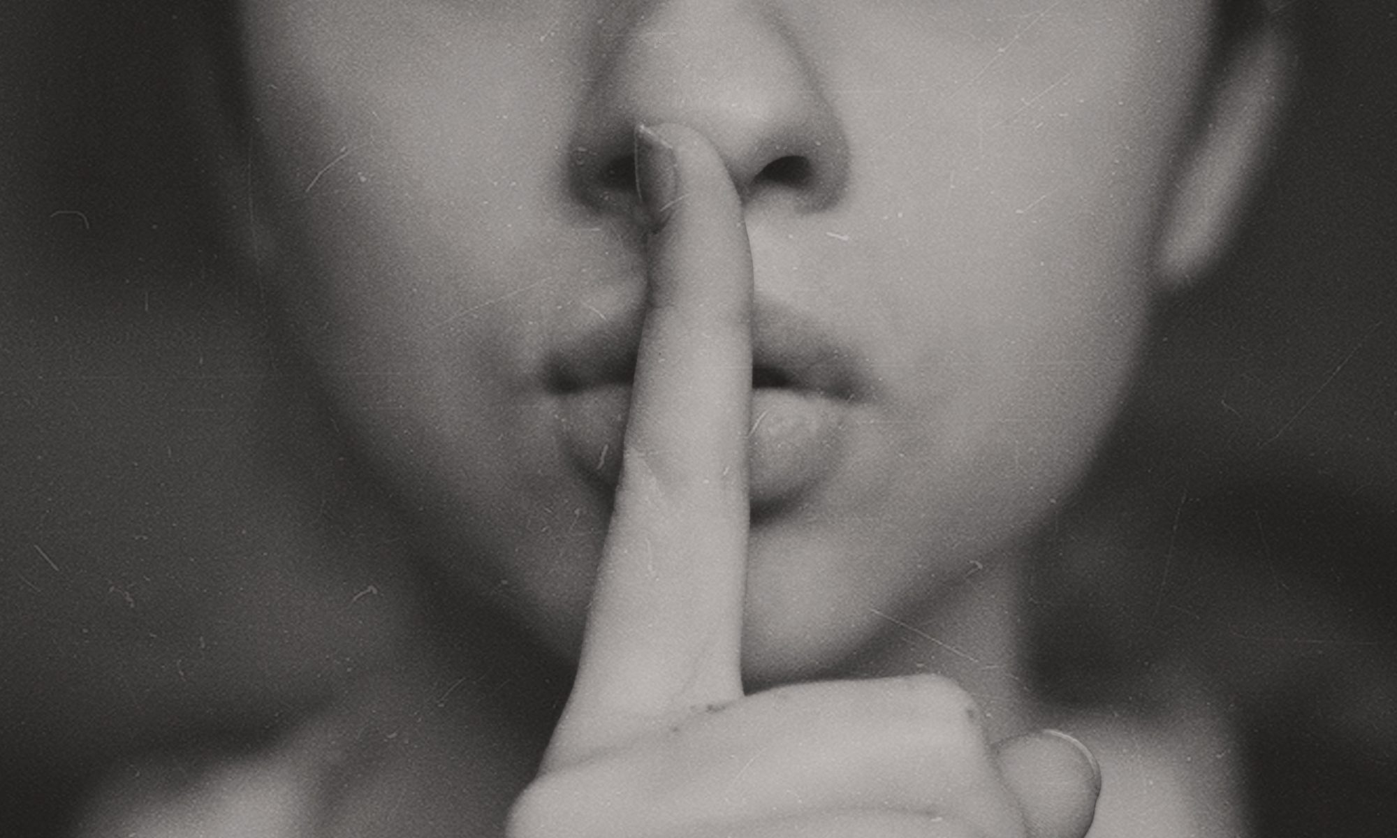 a woman holds her finger to her lips