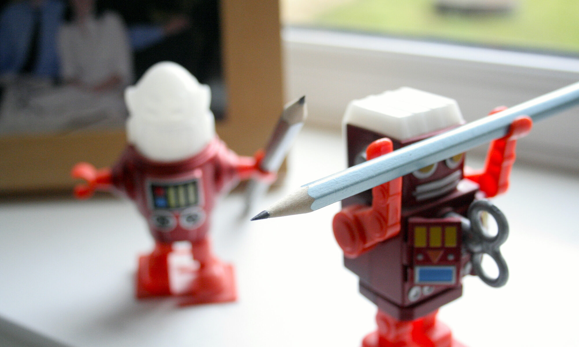 Two Robot Toys Holding Pencils by Heather Fenoughty